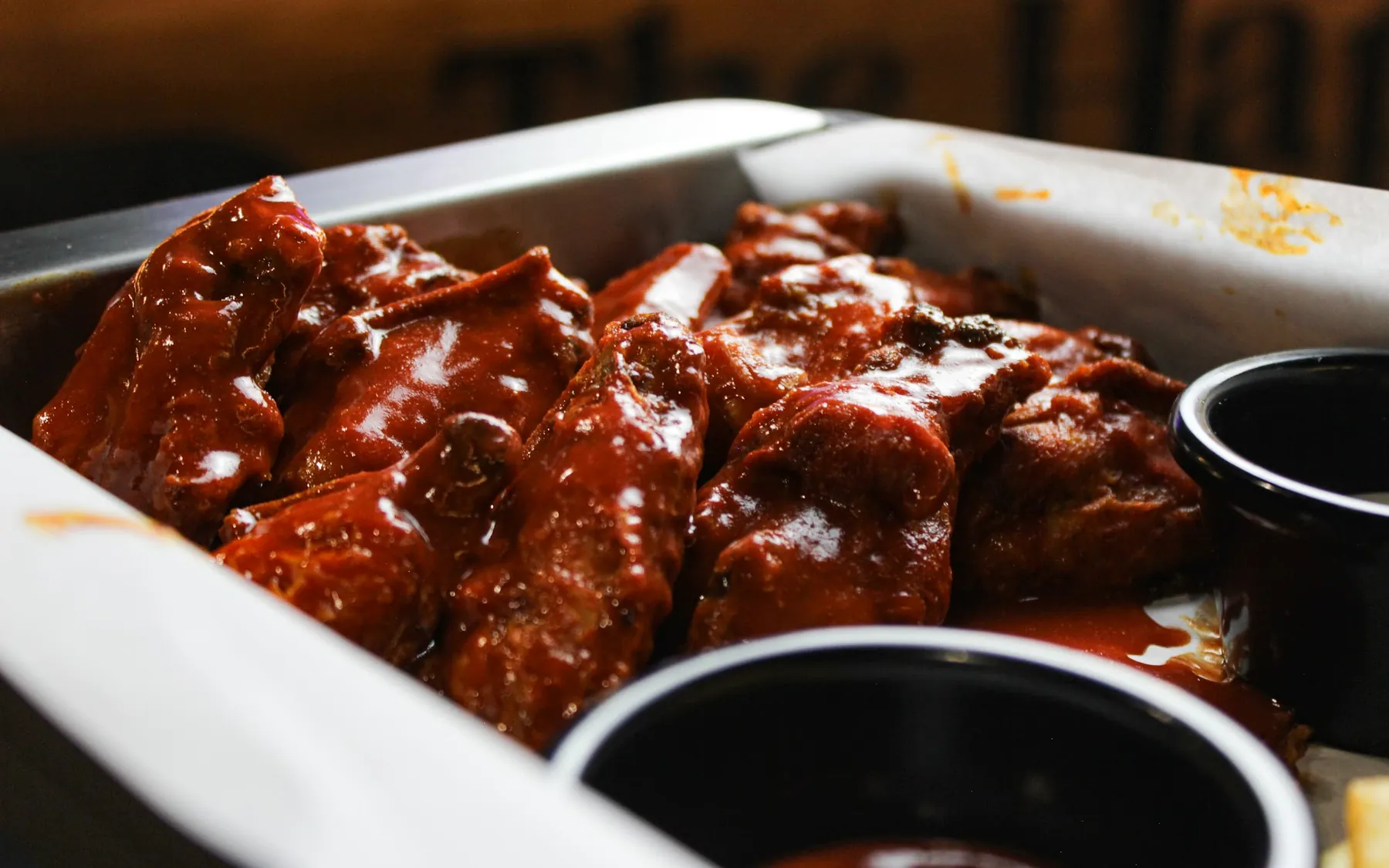 Alitas bañadas en salsa BBQ servidas en charola sobre la mesa